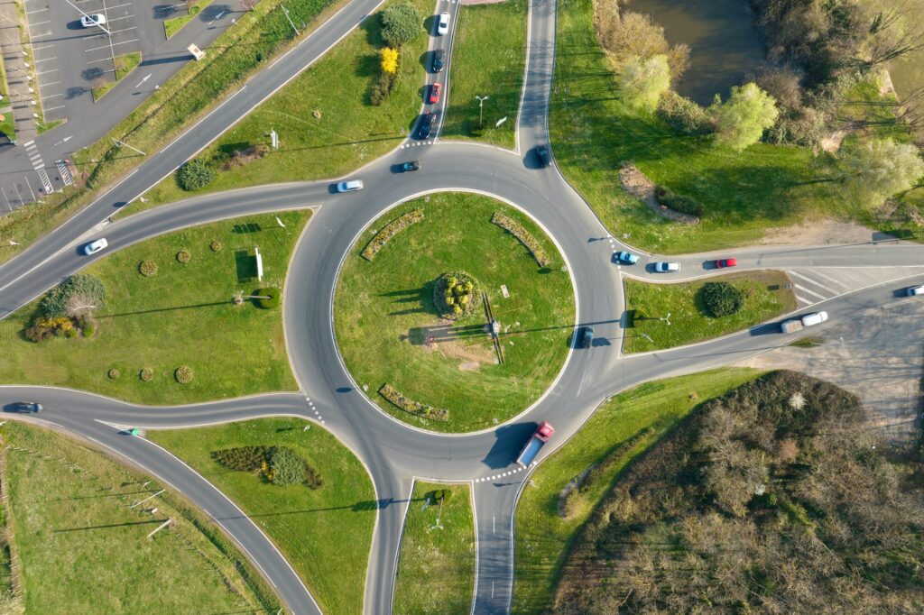 Aerial view of road roundabout intersection with moving heavy traffic.