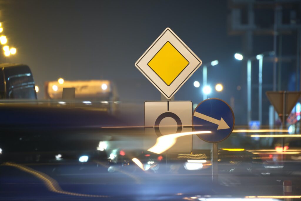 Roundabout road signs with blurred cars on city street traffic at night. Urban transportation
